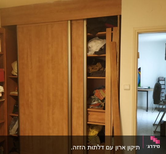 ארון עץ עם דלתות הזזה פתוחות וחלקי עץ בצד